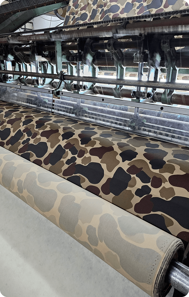 A wide roll of camouflage-patterned fabric on the quilting machine