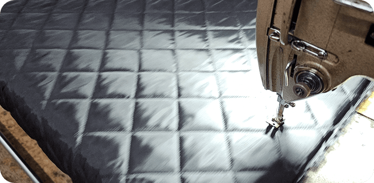 A machinist stitching a black quilted panel on a lock stitch machine
