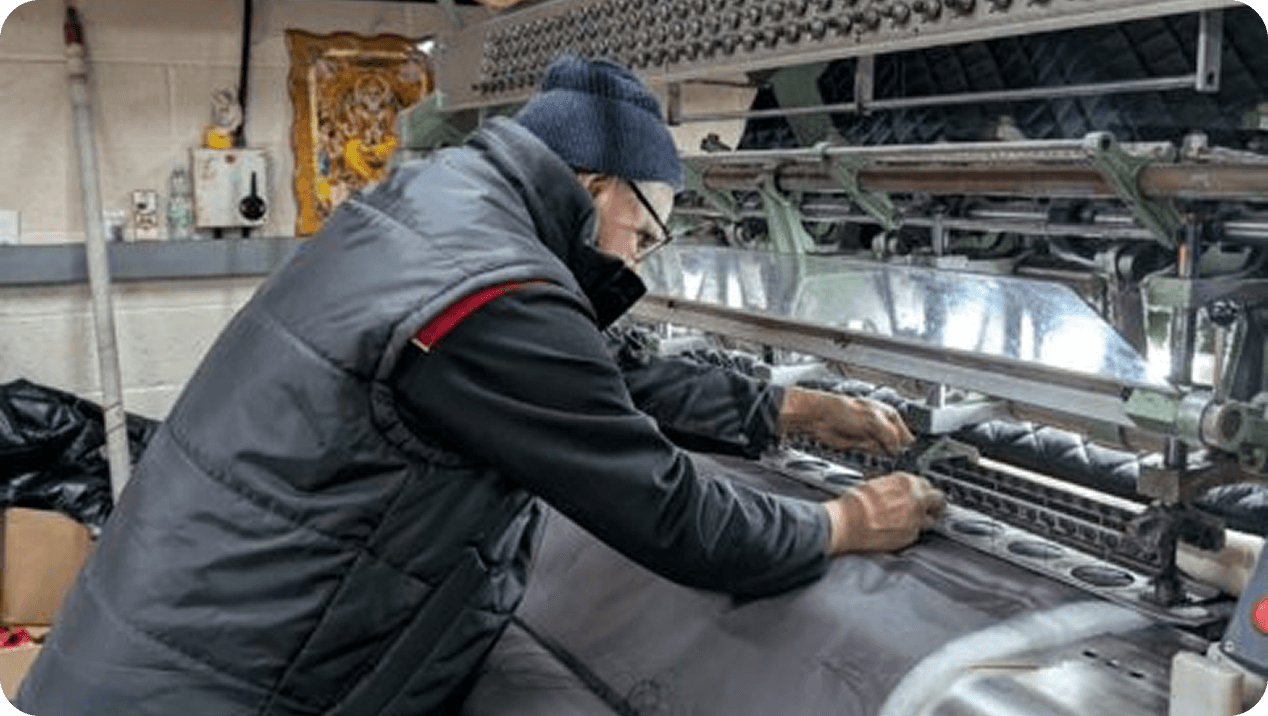 A machinist working at a wide multi-needle quilting machine