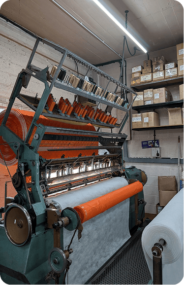A multi-needle quilting machine running orange fabric over wadding