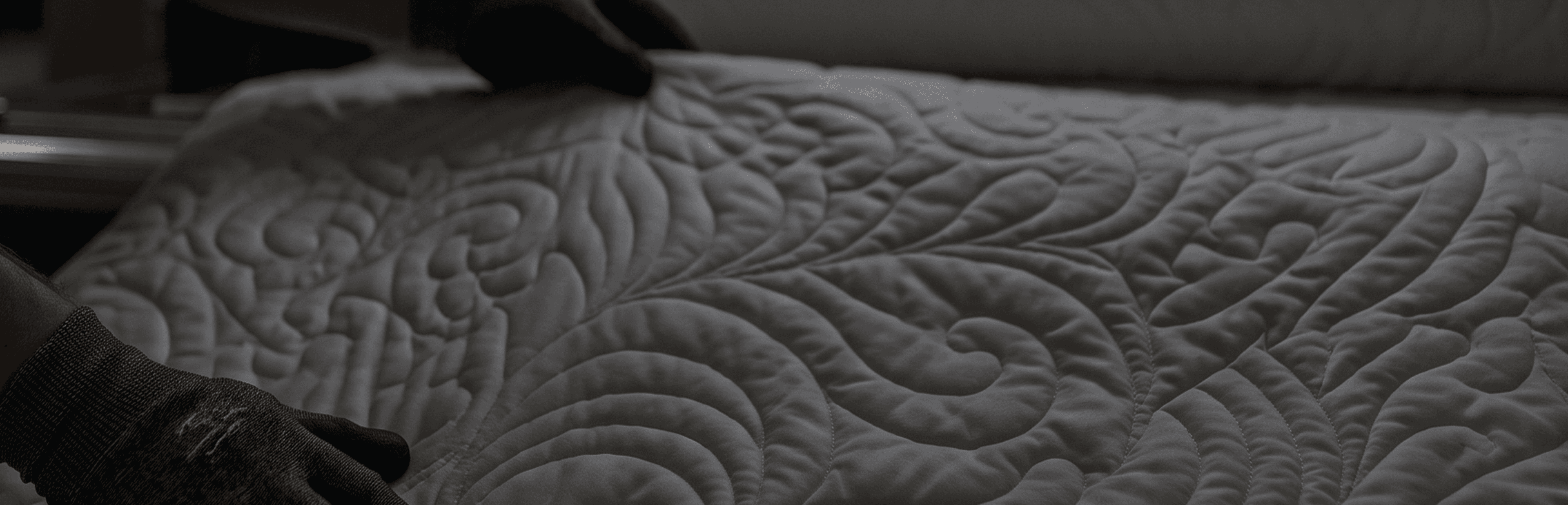 Hands guiding a quilted panel with a swirling feather pattern