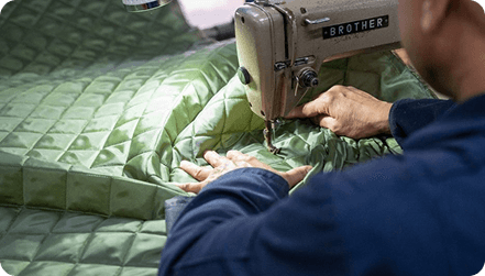 A machinist quilting green fabric on a Brother machine