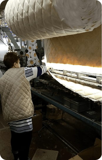 A machinist feeding quilted insulation through the machine
