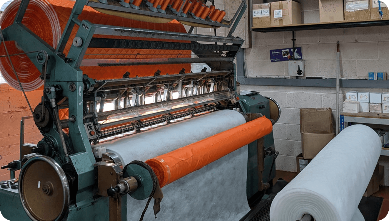 Red quilted fabric running through a multi-needle quilting machine