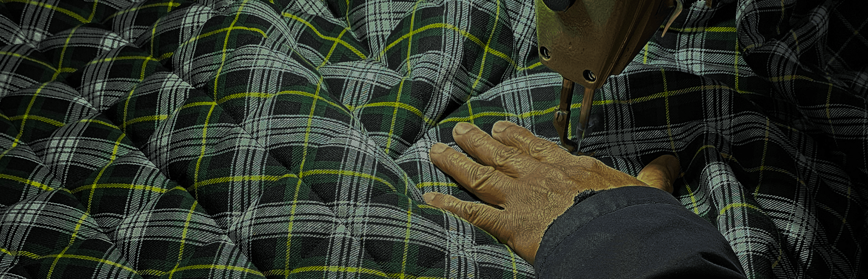 A machinist guiding quilted tartan fabric through a sewing machine