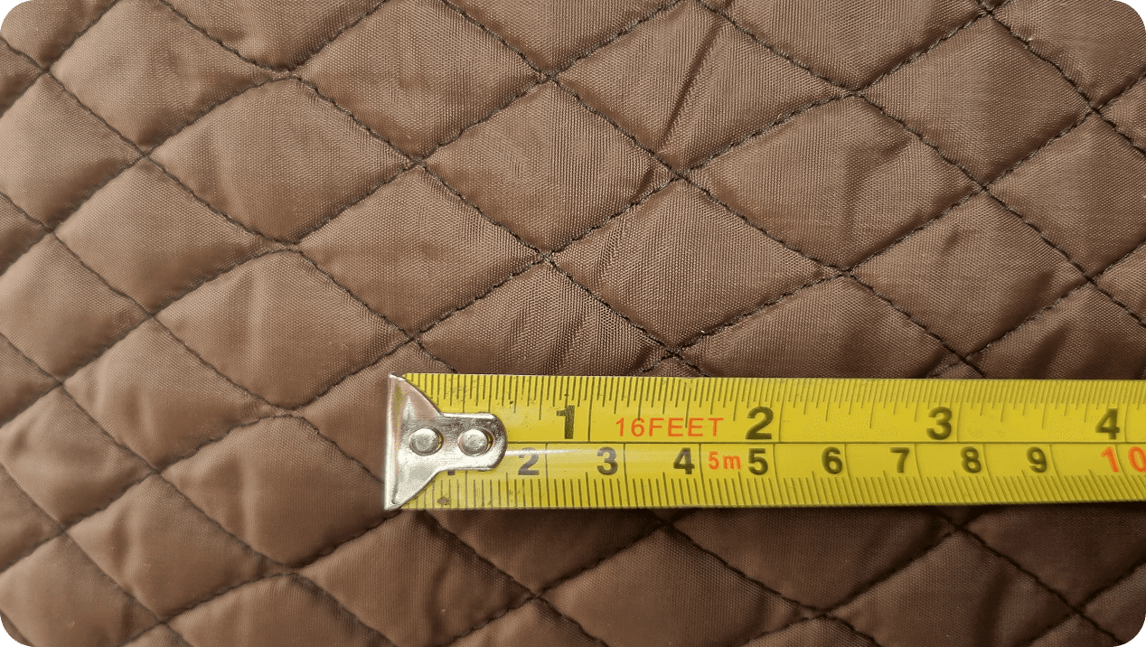 Tape measure laid across brown quilted fabric